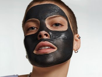 A person with a black charcoal mask covering their entire face.