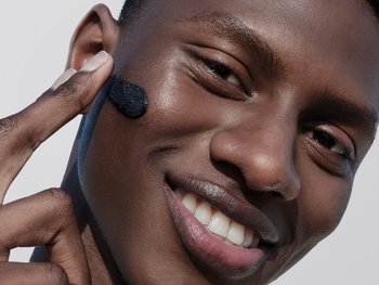 Man smiling and touching his face.