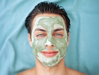Man applying a clay mask to his face.