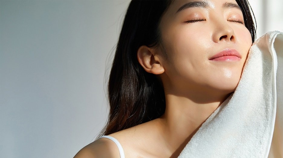 Person gently drying their face with a towel.