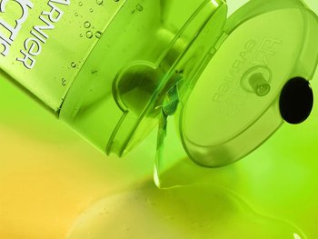 A Garnier Fructis bottle tipped, dispensing green liquid onto a bright green and yellow gradient surface.