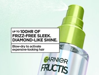 Close-up of a Garnier Fructis spray bottle with copy: "Up to 100hr of frizz-free sleek. Diamond-like shine. Blow-dry to activate expensive-looking hair."