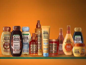 Selection of Garnier Whole Blends hair care products, featuring shampoos, conditioners, and hair masks, formulated with natural ingredients.