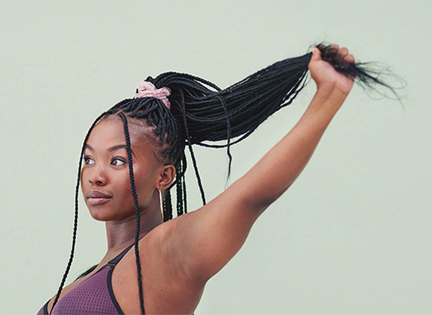 A woman with a high ponytail holds a section of her hair and her hair looks healthy and undamaged.