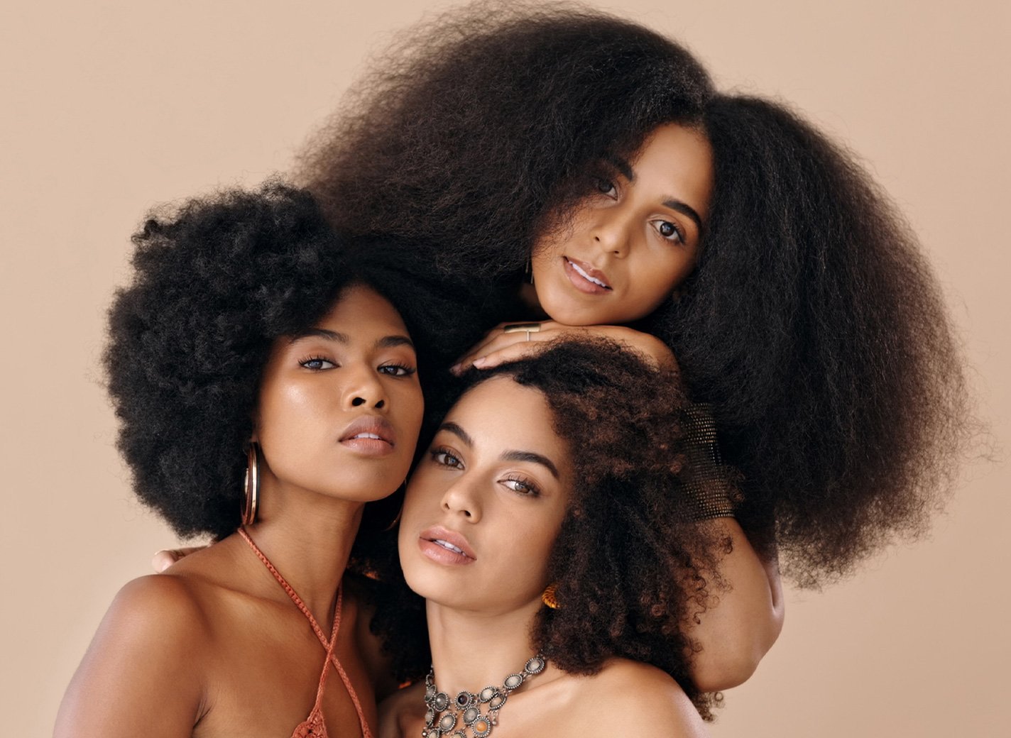 Three models with different types of brown curly and coily hair.