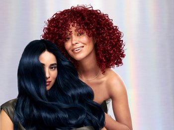 A model with curly red hair next to a model with wavy dark blue hair