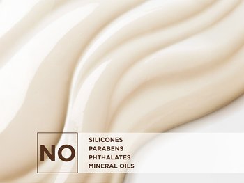 A close-up image of a creamy, light beige product texture with gentle waves. Overlayed on the lower left is a large "NO" symbol, indicating the product is free from "SILICONES," "PARABENS," "PHTHALATES," and "MINERAL OILS."