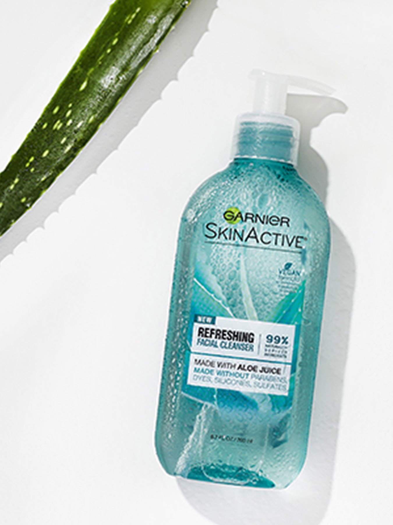 Garnier SkinActive Refreshing Facial Wash with Aloe laying on a white surface with an aloe leaf.