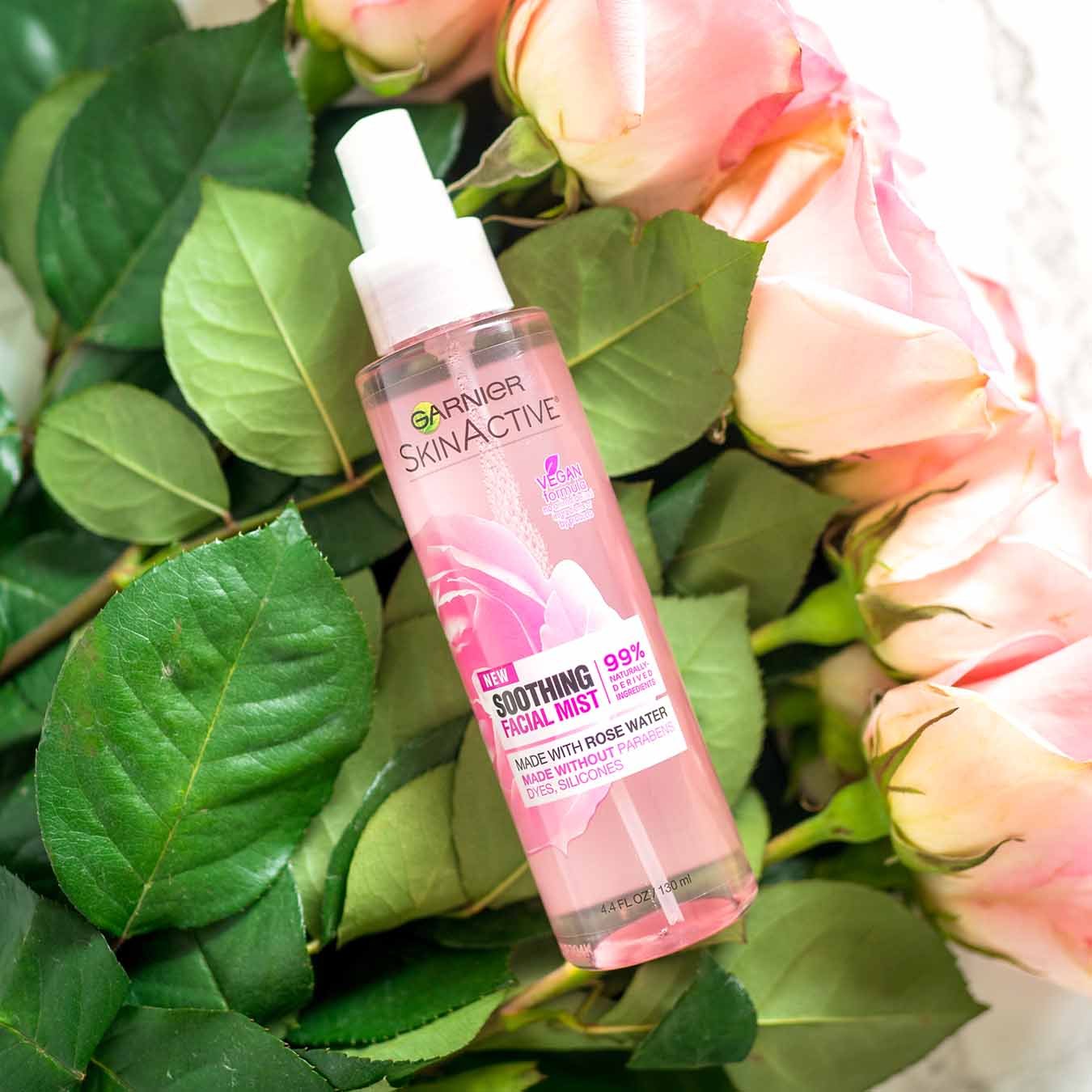 Garnier SkinActive Soothing Facial Mist on a bouquet of pink roses on white marble background.
