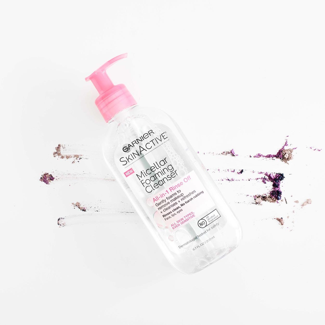 Garnier SkinActive Micellar Foaming Cleanser All-in-1 Rinse Off with pink pump on a white background smudged with tan and purple blush.