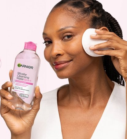 Garnier Micellar Cleansing Water All-in-1 for sensitive skin: woman demonstrating how to remove makeup and hydrate skin for 24H using a cotton pad with the Garnier micellar water bottle.