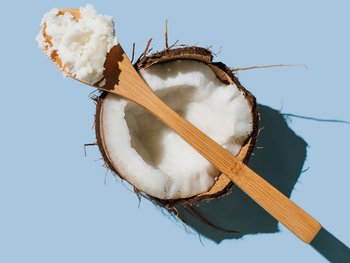 A spoonful of coconut oil on top of an halved coconut.
