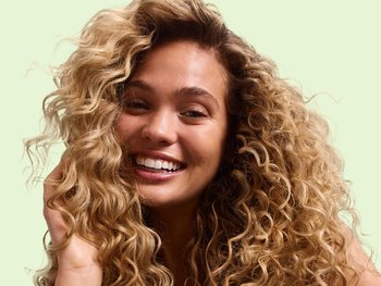 Caucasian female model with wavy, curly blonde hair smiling