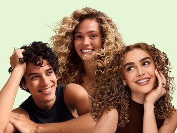 2 female models and 1 male model with wavy and curly hair against a pale green background