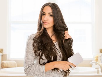 Brown haired woman brushing her hair.