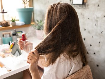 Woman spraying her hair with product.