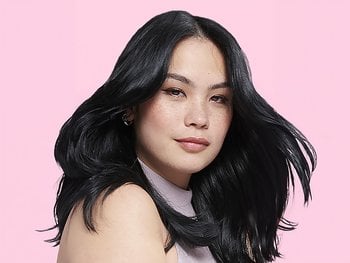 Model with light skin and black hair color against a pink background