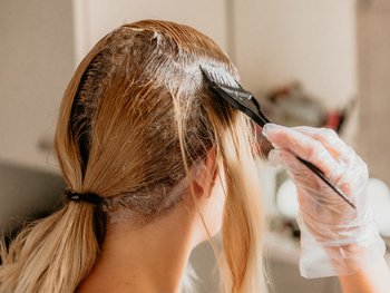 Model applying hair color to roots