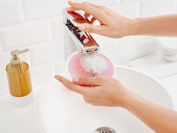 Person wetting eco cleansing pad under sink