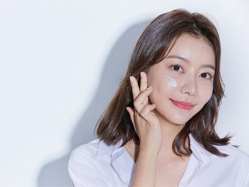 Model with light skin applying moisturizer