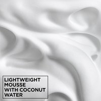 Macro texture shot of lightweight Garnier Fructis hair mousse foam infused with coconut water for hydrating and defining curly hair.