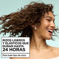 A smiling woman with bouncy, lightweight brown curls, highlighting up to 24H of curl definition for all curl types using Garnier Fructis hair products.
