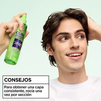 Styling tip for curly hair: man demonstrating the use of Garnier Fructis Curl Shape Defining Spray Gel by spraying once per section for buildable definition.