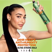 A model using Garnier Fructis Sleek & Shine hairspray, emphasizing its 24-hour hold and anti-humidity protection.