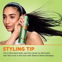 A model demonstrates the use of Garnier Fructis Sleek & Shine hairspray. A styling tip advises using frizz tamer for a slicked-back look.