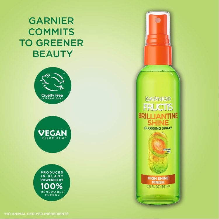 Brilliantine Shine Glossing Spray bottle next to brand’s commitment to “Greener Beauty”. Cruelty-free, vegan, and produced in plant powered by renewable energy. 