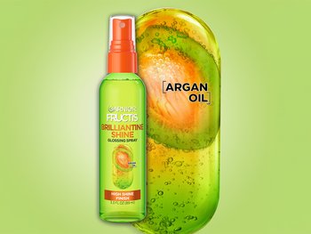 Front shot of a Garnier Fructis Brilliantine Spray next to a graphic of argan oil.