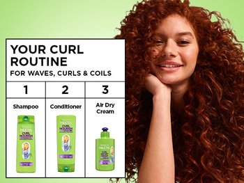 A smiling woman with vibrant red curls alongside a "YOUR CURL ROUTINE" chart for waves, curls, and coils. The three steps shown are: 1. Shampoo, 2. Conditioner, and 3. Air Dry Cream.