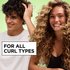 A curly-haired man running his hand through his hair smiles beside a curly-haired woman on a green background next to the text "For All Curl Types," promoting Garnier Fructis Curl Refresher.