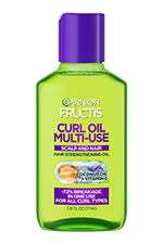 Front view of a lime-green multi-use curl oil bottle with a purple cap, labeled with coconut oil and vitamin E, promising 72% less breakage for all curl types.