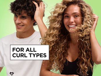 Smiling man and woman with dark and blonde curly hair against a green background, promoting a product for all curl types.