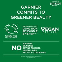 An informational graphic stating "GARNIER COMMITS TO GREENER BEAUTY," featuring logos for Cruelty Free International and "VEGAN FORMULA," and indicating "MADE IN A FACTORY USING 100% RENEWABLE ENERGY." It also prominently states "NO SULFATES SILICONES DRYING ALCOHOL MINERAL OILS ARTIFICAL COLORATNS." The "available at amazon" logo is in the top right.