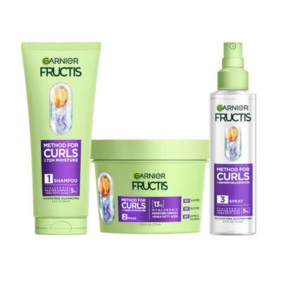 A complete set of Garnier Fructis Method for Curls products is displayed: a light green tube of “Moisture Restoring Shampoo“, a light green tub of “Defining Mask“ and a clear spray bottle of “Reviving Spray" for 48H moisture & definition and for up to 1 week of moisture. All products highlight "Hyaluronic Moisture Complex + Shea Fatty Acids."