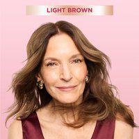 A woman with wavy light brown hair smiling, showcasing the results of the Light Brown root retouch shade.
