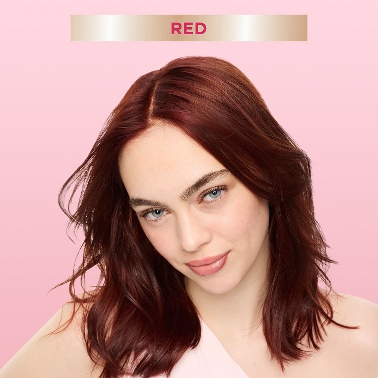 A smiling woman with mid-length, wavy red hair, looking directly at the viewer. A banner at the top indicates ‘Red,' suggesting a hair color result.