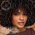 A woman with voluminous curls; text highlights 100% gray coverage and 3x glossier curls for curly hair.