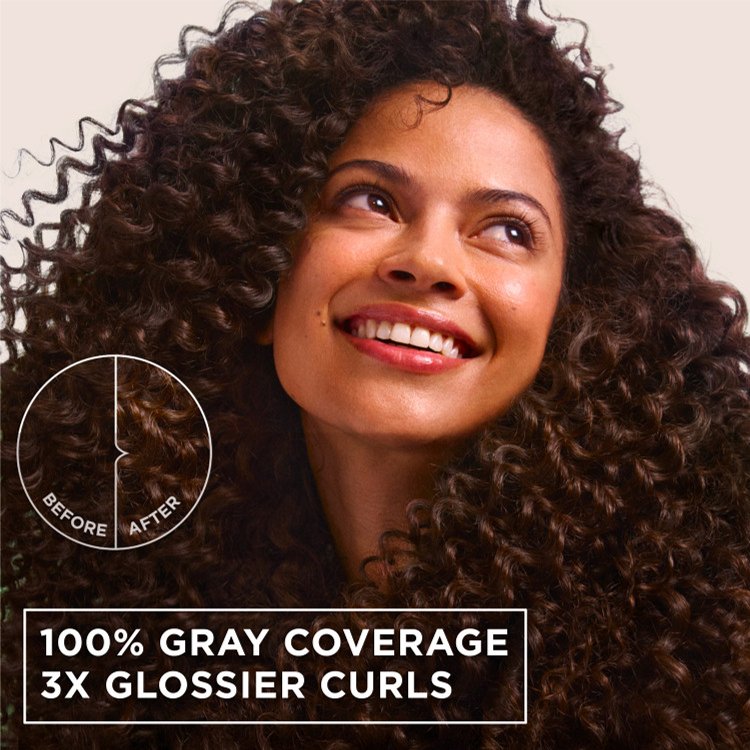 A smiling woman with glossy, dark curly hair, showcasing 100% gray coverage and 3x glossier curls.