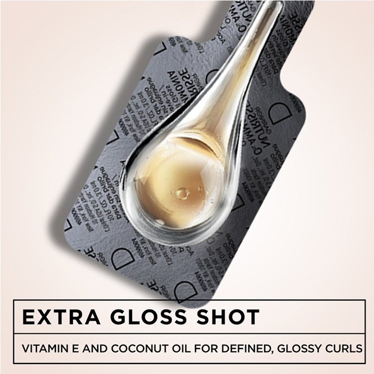 Close-up of the "Extra Gloss Shot" sachet with liquid, highlighting Vitamin E and Coconut Oil.