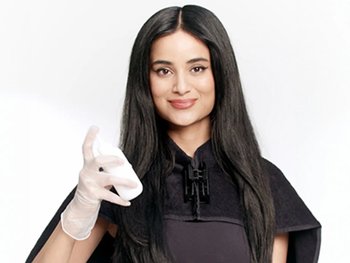 Woman holding applicator bottle with box hair dye and preparing contents for application.