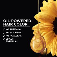 Close-up of a drop of golden oil falling from a sunflower petal, highlighting the oil-powered formula of Garnier Olia hair color.