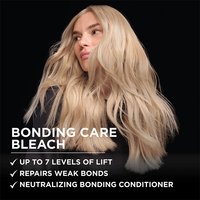 A woman with long, wavy, platinum blonde hair poses against a solid black background, looking slightly downward with a cool, confident expression. Overlaid white text on the left reads: "BONDING CARE BLEACH" followed by a bulleted claim list: "✓ Up to 7 Levels of Lift ✓ Repairs Weak Bonds ✓ Neutralizing Bonding Conditioner."
