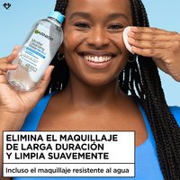 Smiling woman with braided hair using a cotton pad and micellar water bottle, captioned "Removes Longwear Makeup & Gently Cleanses
