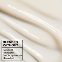 Macro texture of creamy white Garnier Whole Blends Miracle Nectar leave-in treatment, blended without parabens, phthalates, mineral oil, or DMDM hydantoin.