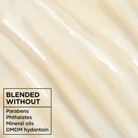 Close-up texture of Garnier Whole Blends Honey Treasures shampoo: creamy white formula blended without parabens, phthalates, mineral oils, or DMDM hydantoin for a clean hair care experience.