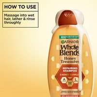 How to use Garnier Whole Blends Repairing Shampoo: product demonstration showing the rich, creamy lather being dispensed for a thorough massage into wet hair.