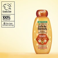 Garnier Whole Blends Honey Treasures Repairing Shampoo hero shot: highlighting cruelty-free international certification, the bee conservancy partnership, and a bottle made of 100% recycled plastic.